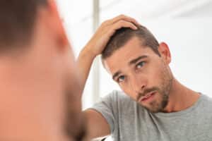 A man examining his hair and contemplating PRP therapy in Greenwood Village, CO