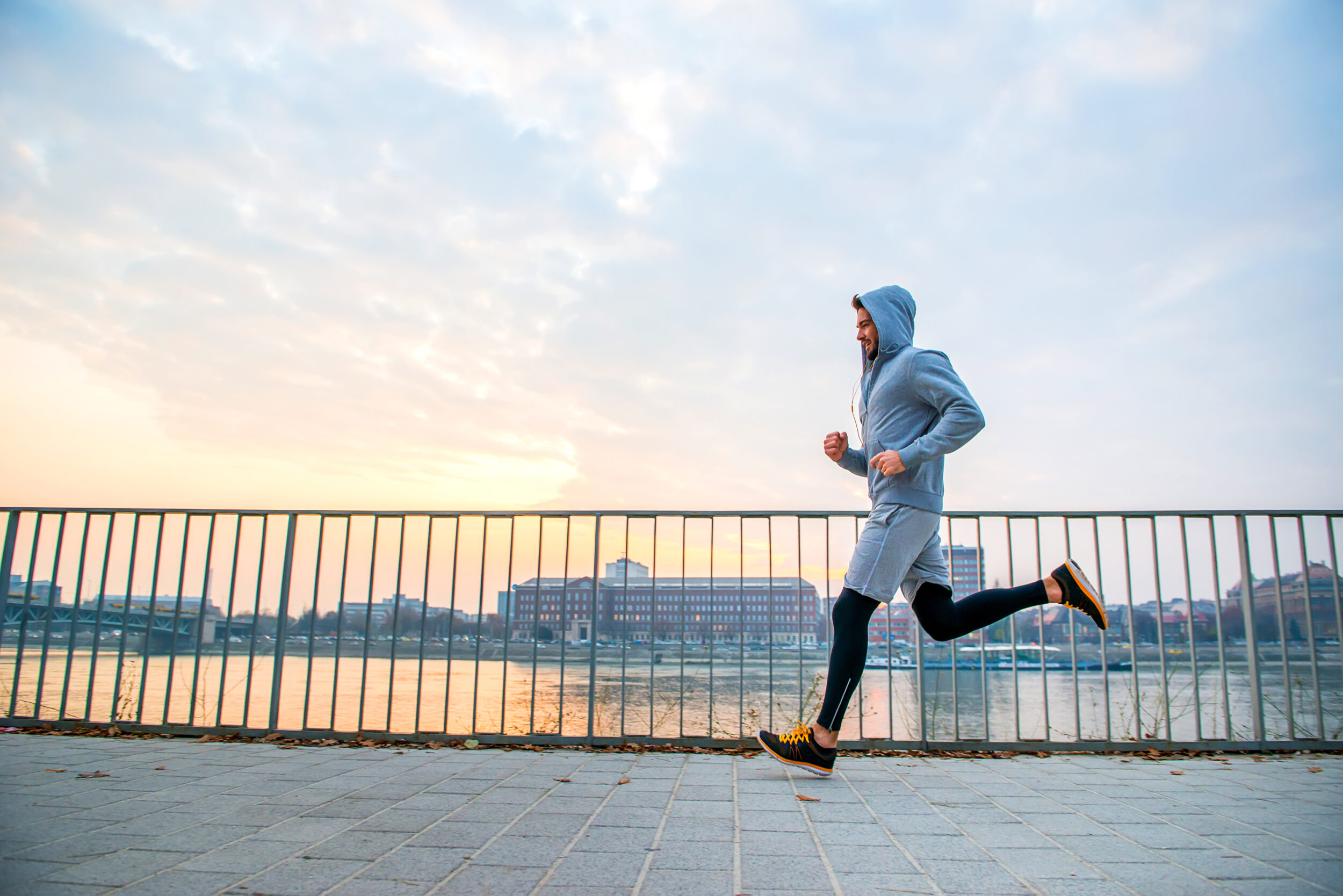 A man running along the water while the sun sets in the background